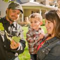 women holding young child standing next to man who are all looking a leaf from tree