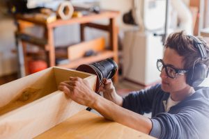 using sander to sand the edge of wood box