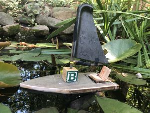 wooden created boat with B letter cube on top of it as sail