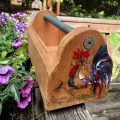 resting hen on the side of wooden tool box on wooden railing