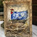 rooster image painted on wood block with hay and chain link protection