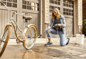 women using worx pressure washer to clean back tire of bike