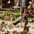 man holding worx trivac blower blowing leafs off of pavers