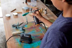 person using airbrush to paint an object blue