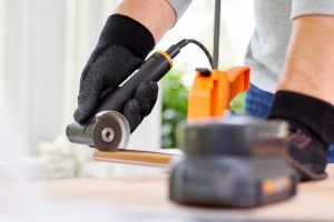 person using angle grinder to cut through a metal pipe