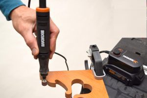 person using rotary tool to sand edges of curved wood