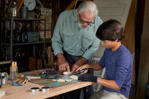 grandfather and grandson using rotary tool on wooden objects