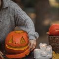 women holding the mouth of cut out pumpkin next to candles