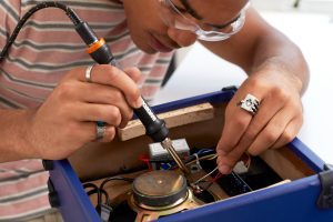 man using wood & metal crafter to solder electronics