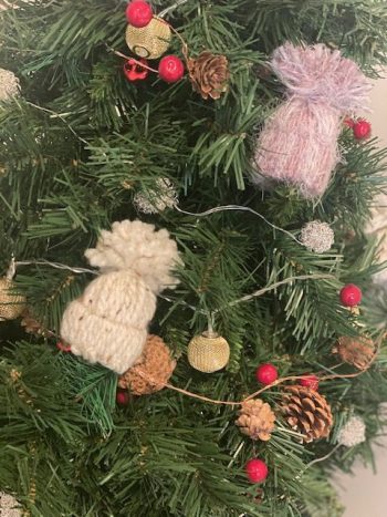 yarn weaved holiday hats on fake christmas tree