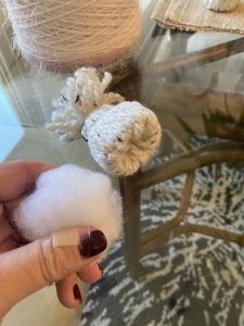 holding stuffing cotton next to little yarn weaved hat