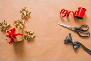 brown paper wrapper present next to red ribbon and scissors