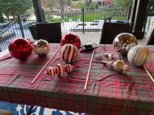 red, white, silver, gold ornaments sitting on red and green plaid table