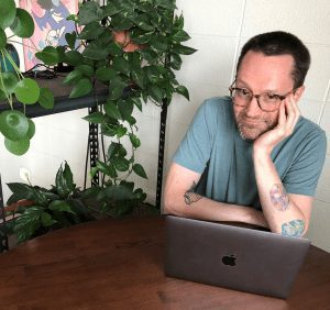 Brett La Frombois sitting in front of computer on desk