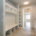 clean and empty home entry way with white walls, shelves and bench
