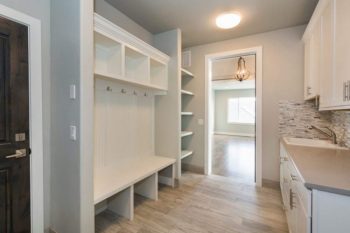 clean and empty home entry way with white walls, shelves and bench