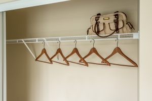 closet with hangers and bag on top shelf