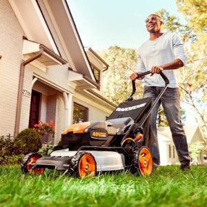 man using Worx WG751 battery powered lawn mower to mow backyard