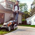 woman mowing edge of lawn using lawn mower with sharp blades