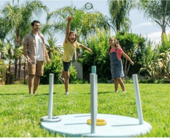 father and two daughters playing ring toss game with homemade game set