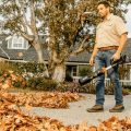Man holding blower blowing off leafs from driveway