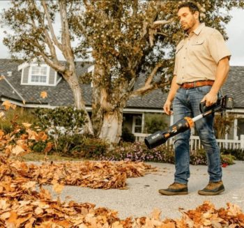 Man holding blower blowing off leafs from driveway