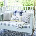 Bed swing on outside porch with blue and white stripped pillows