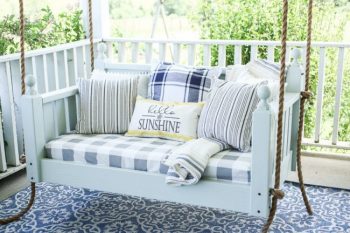 Bed swing on outside porch with blue and white stripped pillows