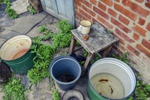 3 water filled buckets next to table and brick wall