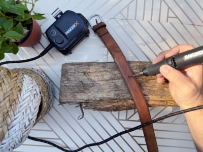 belt being placed on top of old wood peice and rotary tool drilling into it