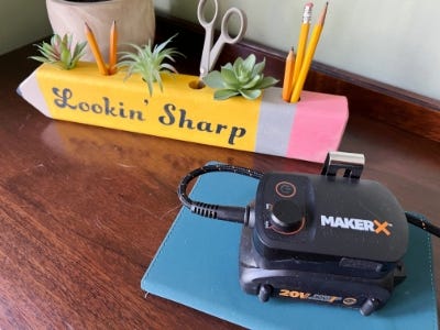 wooden yellow pencil holder sitting with pencils and plants in it next to worx battery charger