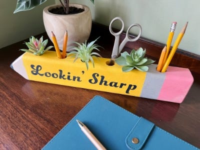 wooden yellow pencil holder sitting with pencils and plants in it