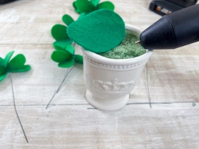 ceramic pot on a table next to the makerx glue gun and green pieces of felt