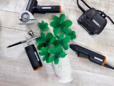 felt clovers in the white ceramic pot on a table next to the makerx air brush, glue gun, rotary cuter and hub