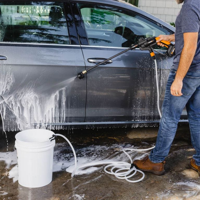 Worx hydroshot cleaning off side of grey car next to bucket of water