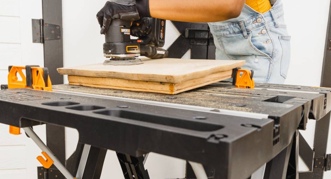 Lady sanding down wood on top of worx pegasus table