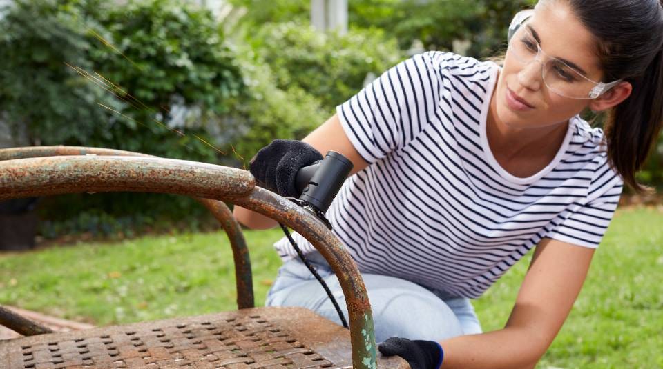 woman using angle grinder to shine rusty chair