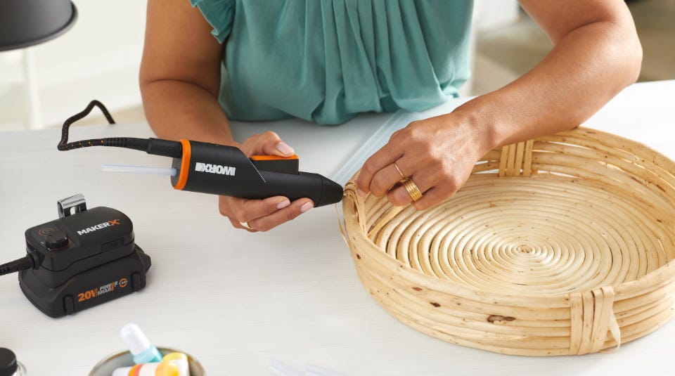 Women holding hot glue gun and glueing woven basket together