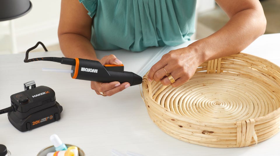 Women holding hot glue gun and glueing woven basket together 