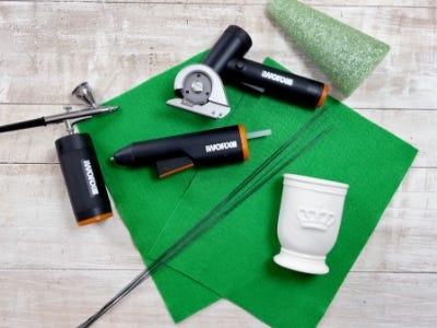 pieces of green felt on a table along with the makerx air brush, glue gun, and rotary cutter