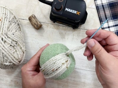 threading yarn through the top and bottom holes wrapping around foam ball