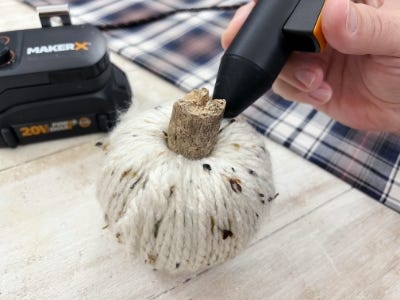 using mini glue gun to glue stick into top of yarn ball