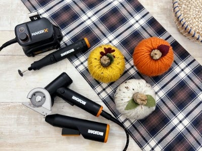 white, orange, yellow yarn ball on plaid cloth next to rotary tool, zipsnip, and mini glue gun