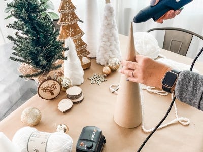 using glue gun to add glue to top of cone next to Christmas decorations