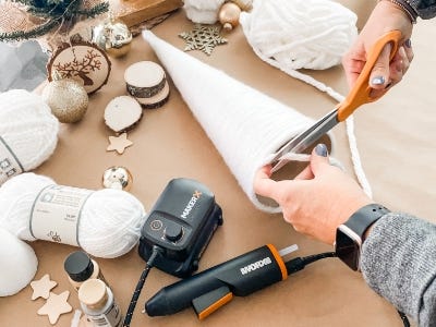 using scissors to cut yarn from bottom of tree