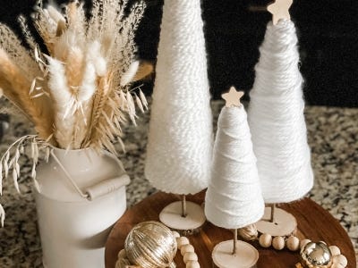 three standing yarn trees with wooden star next to vase with weat