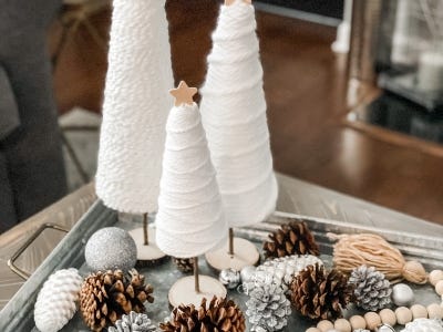 three yarn wrapped trees with wooden star sitting on silver platter