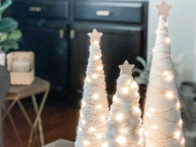 three yarn trees with lights on sitting next to each other