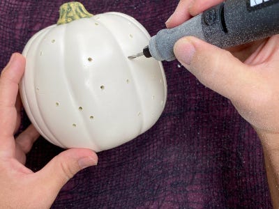 Rotary tool drilling dots into white pumpkin