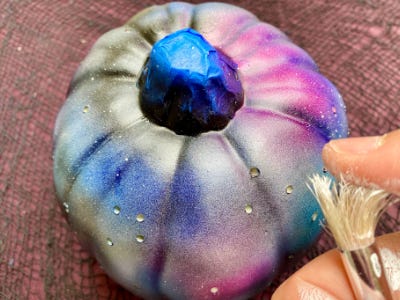 Pink, blue, silver, and white pumpkin being splattered by silver paint